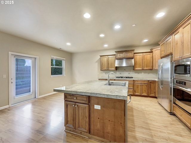 kitchen with recessed lighting, under cabinet range hood, a sink, appliances with stainless steel finishes, and light wood-type flooring