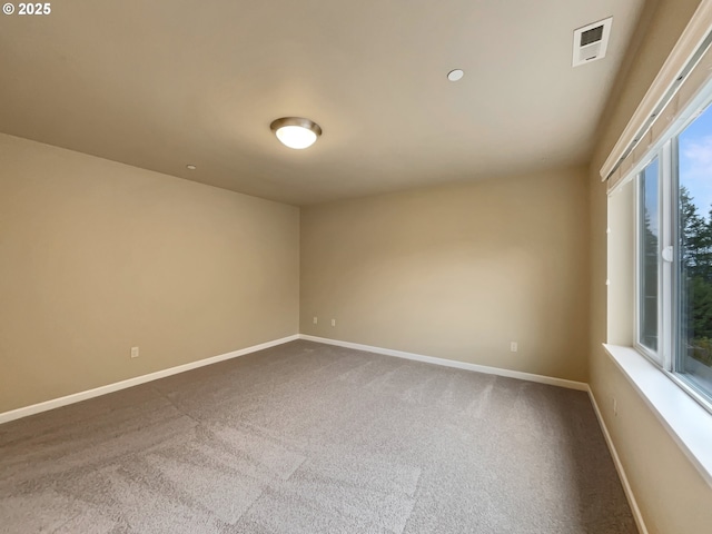 carpeted spare room featuring visible vents and baseboards