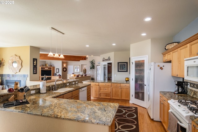 kitchen featuring a sink, a peninsula, light wood-style flooring, white appliances, and recessed lighting