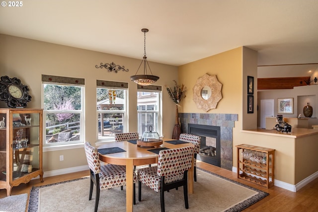 dining space with a wealth of natural light, a fireplace, wood finished floors, and baseboards