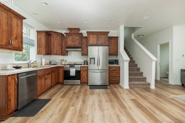 1937 NE 7th Dr, Lincoln City, OR 97367 - kitchen featuring stainless steel appliances, a sink, light wood-style flooring, exhaust hood, and light countertops