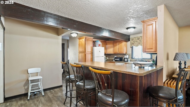 468 E Sunset Dr, Hermiston, OR 97838 - kitchen with freestanding refrigerator, dark wood-style floors, backsplash, a peninsula, and a textured ceiling