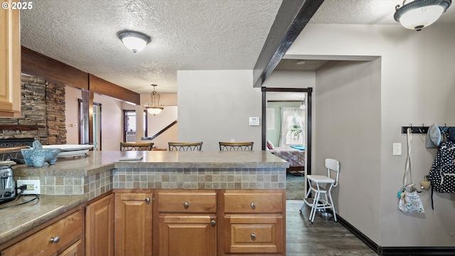 468 E Sunset Dr, Hermiston, OR 97838 - kitchen featuring a textured ceiling, dark wood-style flooring, plenty of natural light, a peninsula, and brown cabinetry