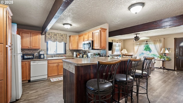 468 E Sunset Dr, Hermiston, OR 97838 - kitchen featuring white appliances, beamed ceiling, wood finished floors, a kitchen breakfast bar, and tasteful backsplash