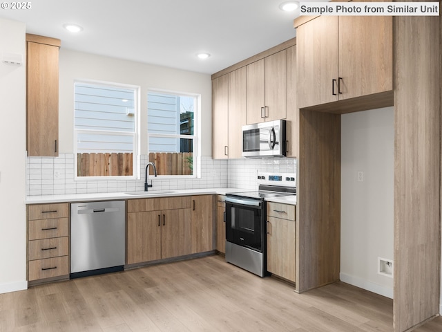 4138 NE 14th Ave, Portland, OR 97211 - kitchen with a sink, backsplash, light wood-style floors, light countertops, and appliances with stainless steel finishes
