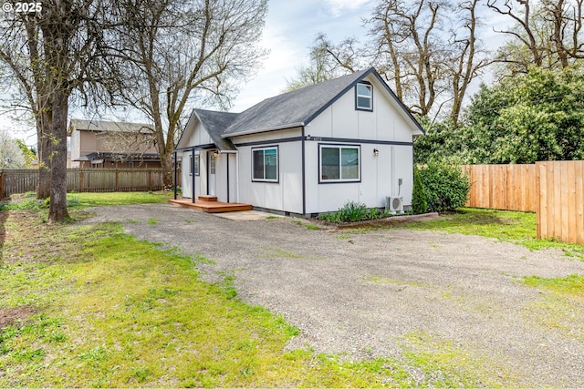 exterior space with ac unit, board and batten siding, fence, and roof with shingles