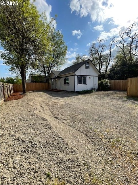 rear view of property featuring fence and driveway