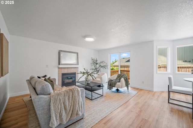 2952 NW Ogden St, Camas, WA 98607 - living area with a tile fireplace, light wood finished floors, baseboards, and a textured ceiling