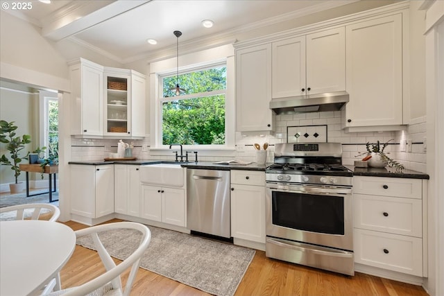 1520 SE 54th Ave, Portland, OR 97215 - kitchen with appliances with stainless steel finishes, under cabinet range hood, a sink, dark countertops, and crown molding