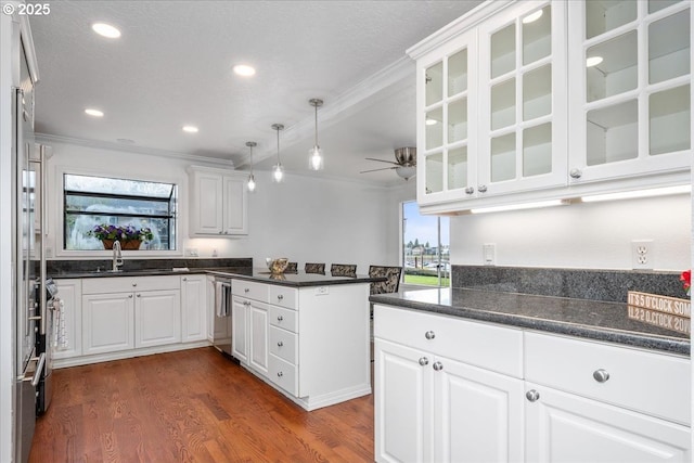 kitchen with a sink, ceiling fan, white cabinets, a peninsula, and ornamental molding