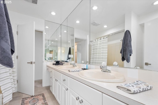 bathroom featuring recessed lighting, double vanity, and a sink