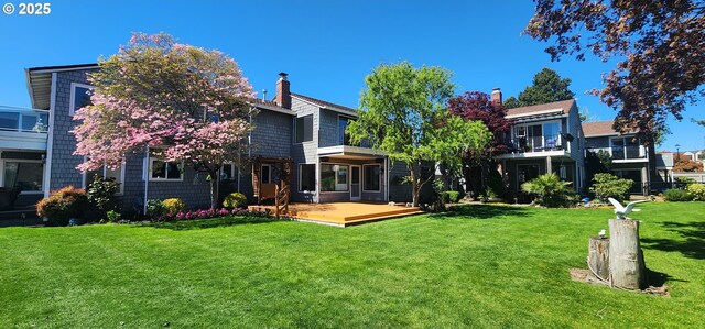 back of house featuring a lawn, a chimney, and a wooden deck