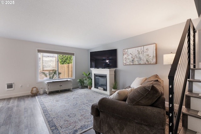 29460 SW Volley St Unit 72, Wilsonville, OR 97070 - living area with heating unit, a glass covered fireplace, wood finished floors, baseboards, and stairway
