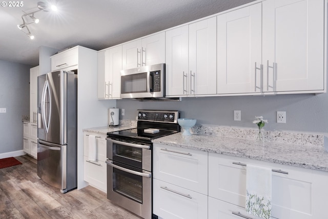 29460 SW Volley St Unit 72, Wilsonville, OR 97070 - kitchen featuring light wood-type flooring, white cabinets, light stone countertops, and stainless steel appliances