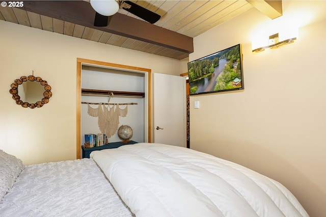 bedroom with beamed ceiling, wood ceiling, a closet, and ceiling fan