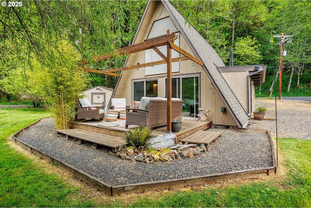 back of house with a wooden deck, roof with shingles, a view of trees, a storage shed, and a yard