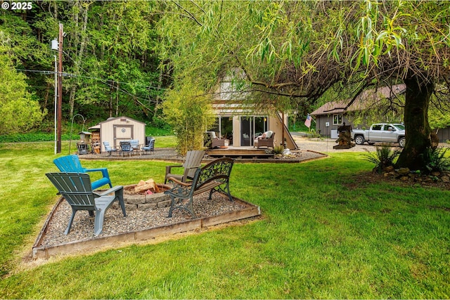 view of grassy yard with a fire pit, an outdoor structure, and a wooden deck