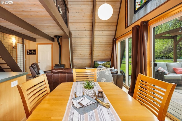 dining room with a wood stove, beamed ceiling, and stairway