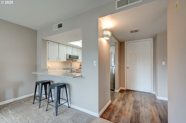 kitchen with stainless steel microwave, a kitchen bar, and visible vents