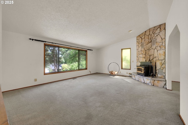 1770 W 28th Ave, Eugene, OR 97405 - unfurnished living room featuring lofted ceiling, carpet floors, a wood stove, and a textured ceiling