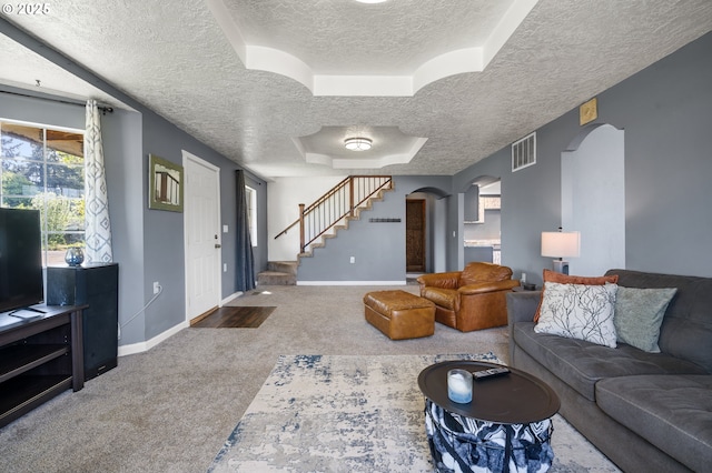 living room featuring a textured ceiling, visible vents, carpet floors, baseboards, and arched walkways