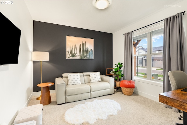 carpeted living room featuring an accent wall and baseboards