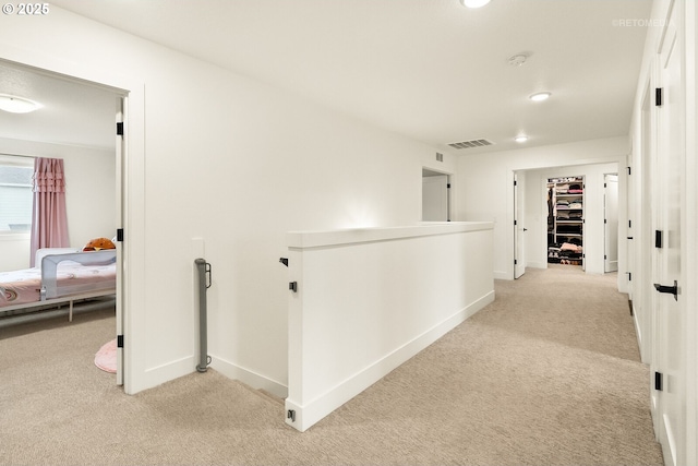 corridor featuring light colored carpet, baseboards, visible vents, and an upstairs landing