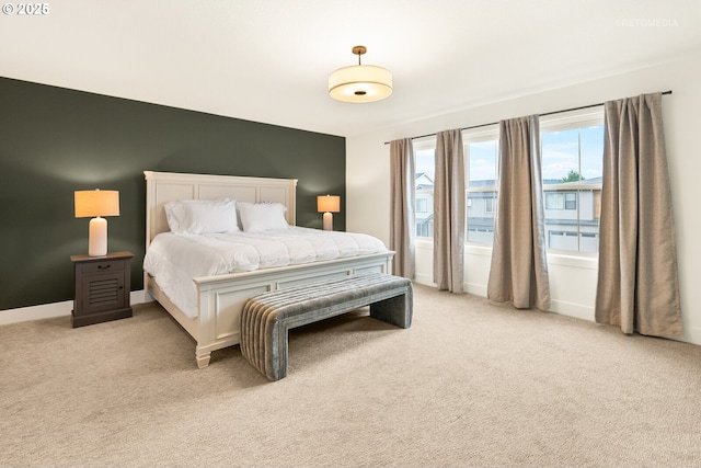 bedroom with baseboards and light colored carpet