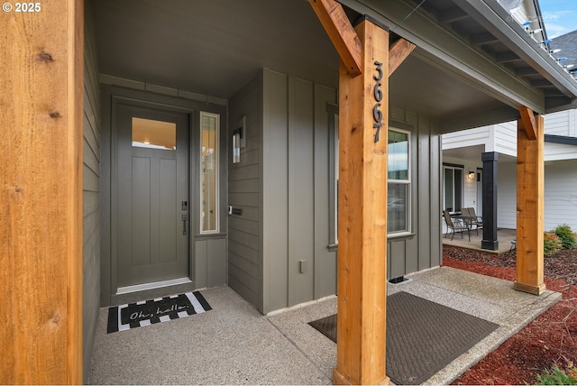 view of exterior entry with covered porch and board and batten siding