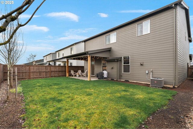 rear view of property featuring a yard, central AC unit, a fenced backyard, and a patio area