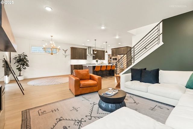 living room with a chandelier, recessed lighting, light wood-style flooring, and stairs