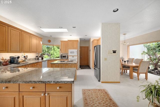 22750 SW Rosedale Rd, Beaverton, OR 97078 - kitchen featuring white appliances, stone countertops, a skylight, a peninsula, and recessed lighting