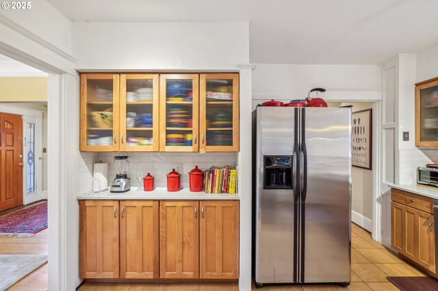 1917 NE Fremont St, Portland, OR 97212 - kitchen with stainless steel fridge, backsplash, light countertops, glass insert cabinets, and brown cabinetry