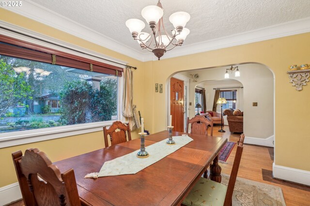 1917 NE Fremont St, Portland, OR 97212 - dining space with arched walkways, a chandelier, ornamental molding, wood finished floors, and a textured ceiling