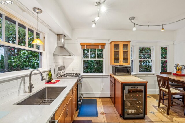 1917 NE Fremont St, Portland, OR 97212 - kitchen featuring wine cooler, stainless steel gas range oven, wall chimney range hood, a sink, and butcher block counters