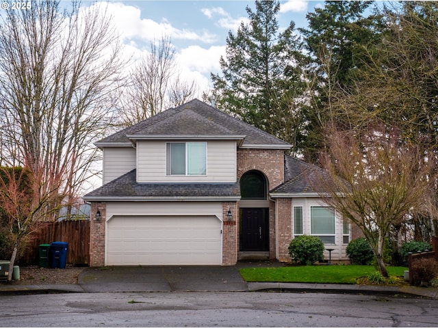 traditional-style home with a garage, brick siding, fence, driveway, and roof with shingles