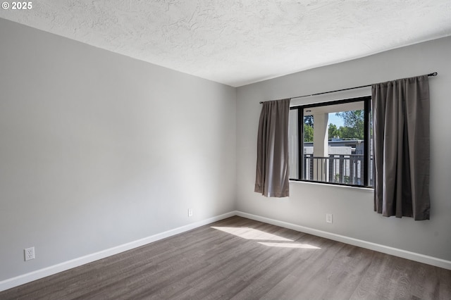 empty room with dark wood-style floors, baseboards, and a textured ceiling