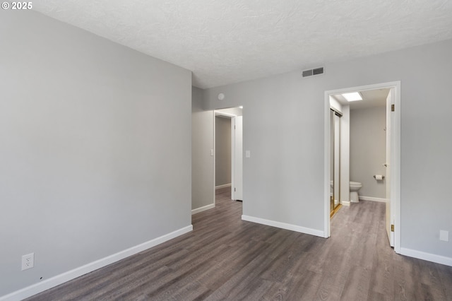 spare room with dark wood-style floors, baseboards, and a textured ceiling
