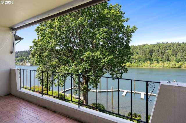 balcony featuring a water view and a forest view