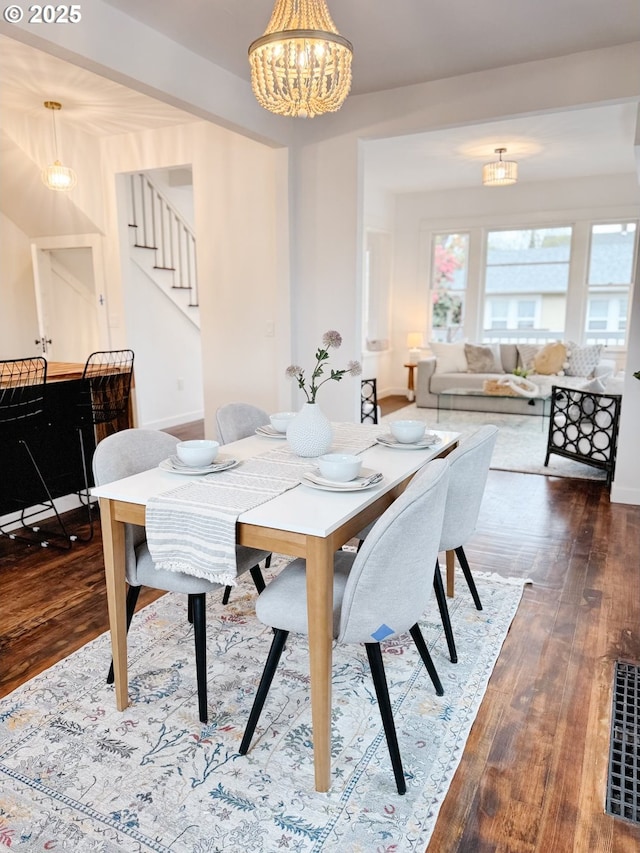 dining area featuring a chandelier, stairs, baseboards, and dark wood-style flooring