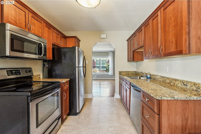 kitchen featuring light tile patterned flooring, stainless steel appliances, light stone counters, and sink