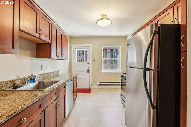 kitchen with light stone countertops, appliances with stainless steel finishes, a baseboard heating unit, sink, and light tile patterned floors