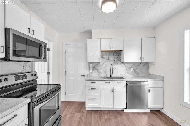 3114 Delaware St, Longview, WA 98632 - kitchen featuring tasteful backsplash, a sink, stainless steel appliances, white cabinetry, and light wood-type flooring