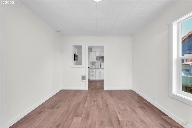 3114 Delaware St, Longview, WA 98632 - unfurnished room with visible vents, crown molding, light wood-type flooring, a sink, and baseboards