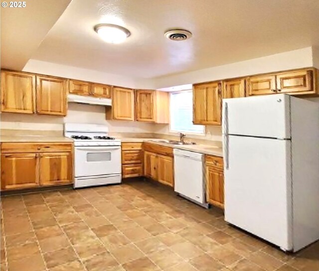 kitchen with white appliances, visible vents, light countertops, under cabinet range hood, and a sink