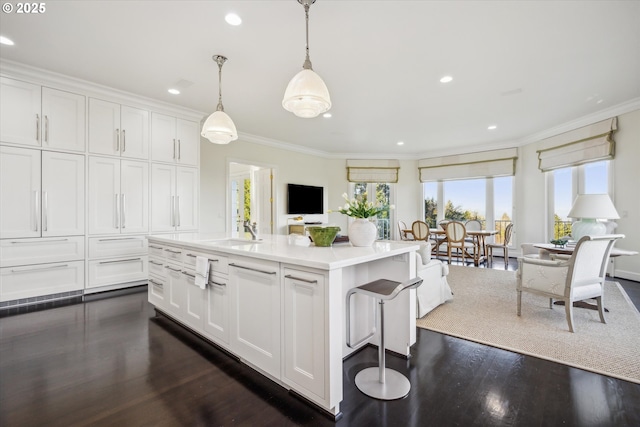 kitchen with white cabinets, a center island, sink, hanging light fixtures, and crown molding