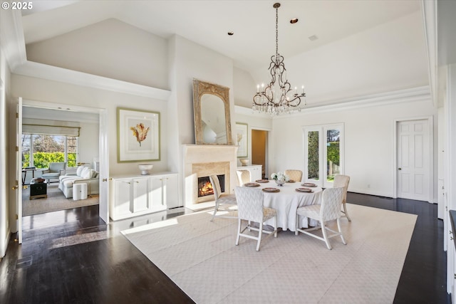 dining space featuring high vaulted ceiling, a wealth of natural light, a premium fireplace, and hardwood / wood-style floors