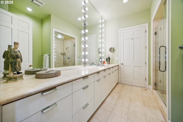 bathroom featuring tile patterned flooring, a shower with door, and vanity