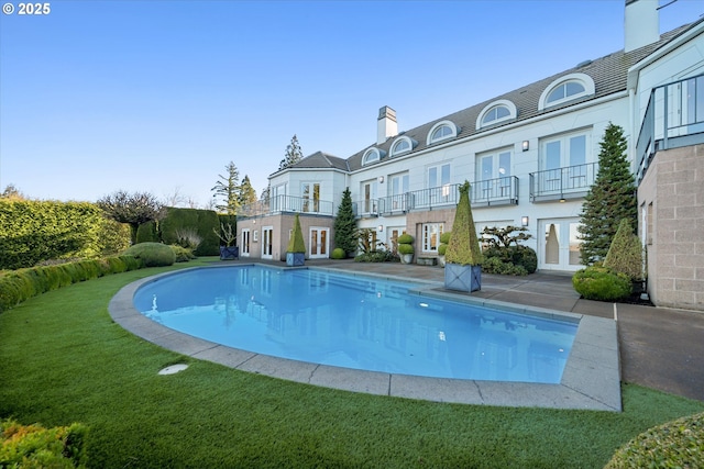 view of swimming pool with french doors and a yard