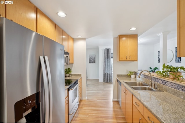 kitchen with sink, light hardwood / wood-style flooring, light stone countertops, and appliances with stainless steel finishes